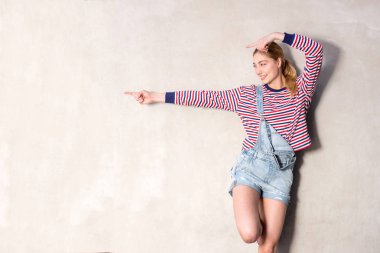 Mutlu sarışın kız portresi duvardaki boş yeri işaret ediyor.