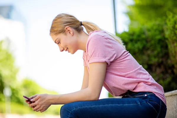 Side Portret Van Tiener Meisje Zitten Buiten Kijken Naar Mobiele — Stockfoto