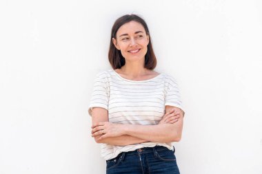 Beyaz arka planda duran, kollarını kavuşturup bakan yaşlı kadının portresi.