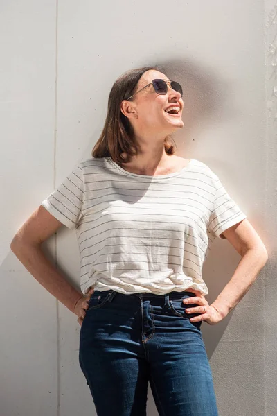 Portrait happy middle aged woman laughing with sunglasses and looking up by white background