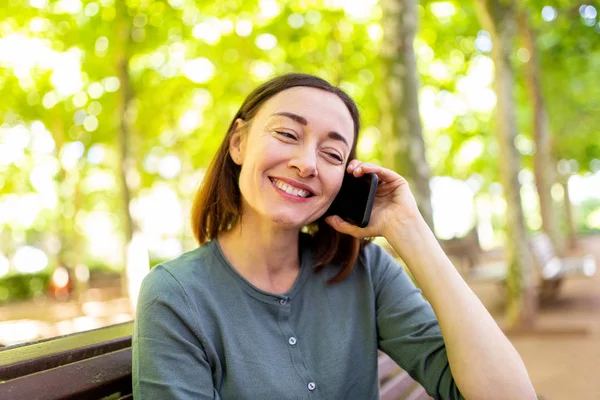 Portrait Smiling Middle Aged Woman Sitting Park Talking Cellphone — Stockfoto