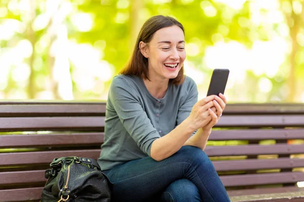 Portrait Happy Older Woman Sitting Park Looking Mobile Phone — Stockfoto