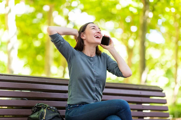 Portrait Cheerful Woman Sitting Park Bench Talking Cellphone — Stockfoto