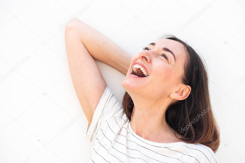 Close up portrait of attractive older woman laughing by white background with hand in hair