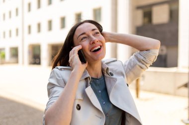 Şehirde telefonuyla gülümseyen çekici yaşlı kadın portresi.