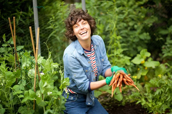 Portrait of happy gardener harvesting carrots from garden