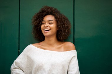 Yeşil arka planda gülümseyen Afrikalı Amerikalı genç bir kadının portresi 