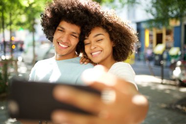 Şehirde fotoğraf çeken mutlu afro çiftin portresi.