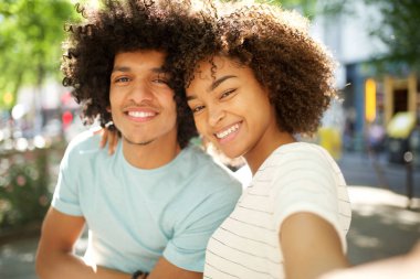 Mutlu bir afro çiftin portresi şehrin dışında selfie çekiyor.