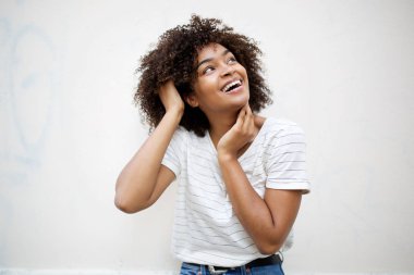 Portrait of cheerful young african american woman laughing and looking up by white background