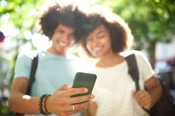 肖像画笑顔若いアフリカ系アメリカ人のカップル立って外で携帯電話を見て — ストック写真