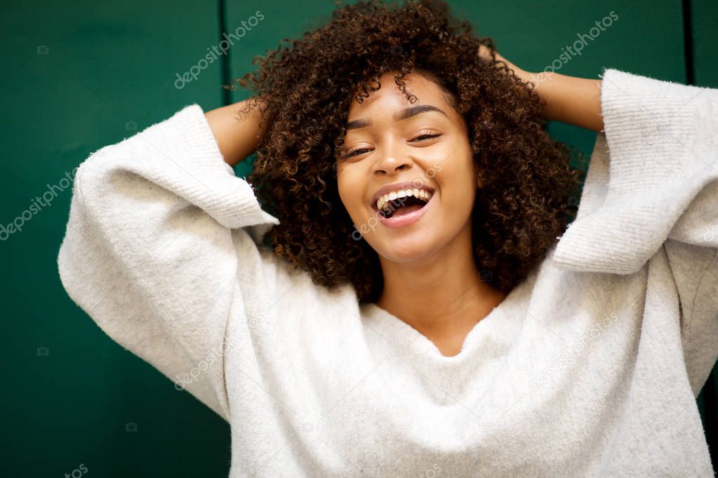 Close up portrait of laughing young african american with hands in hair