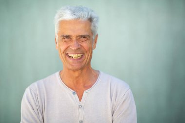 Yeşil duvarda gülümseyen yakışıklı yaşlı adamın ön portresini kapat.