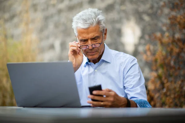 Ritratto Uomo Affari Seduto Fuori Con Computer Portatile Guardando Cellulare — Foto Stock