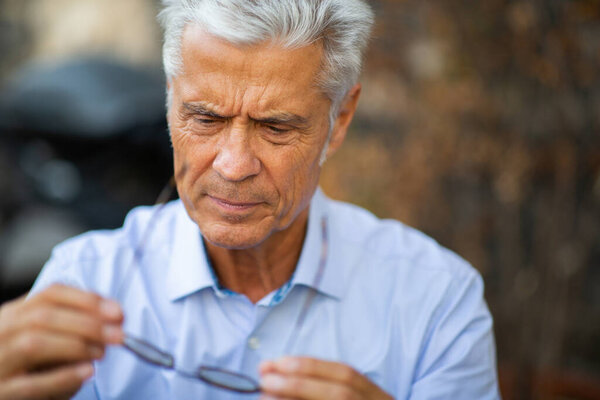 Close up portrait older man looking at eyeglasses 