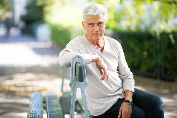 Portrait handsome older man sitting on park bench