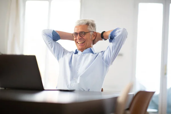 Portrait of relaxed businessman looking at pop with hands behind head