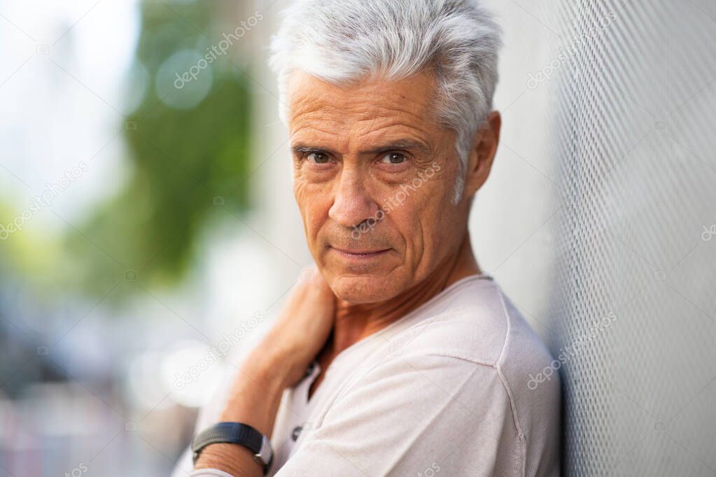 Close up portrait older man leaning against wall outside
