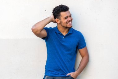 Beyaz duvara yaslanmış, başını çevirmiş mutlu, genç bir ırkın portresi.