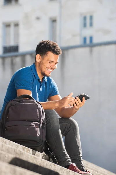 幸せな若いです混合レース男座っています上のステップ見ます携帯電話 — ストック写真