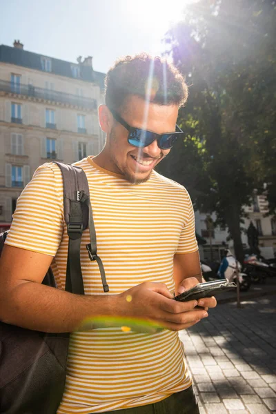 Blisko Szczęśliwy Młody Afrykanin Amerykański Człowiek Torbą Patrząc Telefon Mieście — Zdjęcie stockowe