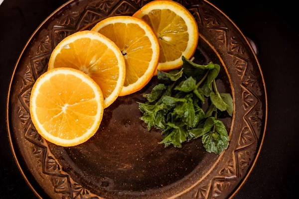 Dilimlenmiş portakallar naneli bir tabakta yatıyor.