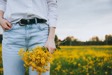Çiçekleri yeşil arka planda tutan kadın.