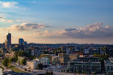 Gün batımında Vilnius Panoraması. Şehir binaları. Ufuktaki gökdelenler. Şehrin üzerinde mavi gökyüzü. Gün batımında bulutlar ve güneş. Yaz akşamı. Hafta sonu sakin bir gün.