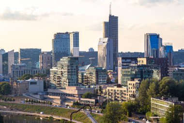 Gün batımında Vilnius Panoraması. Şehir binaları. Ufuktaki gökdelenler. Şehrin üzerinde mavi gökyüzü. Gün batımında bulutlar ve güneş. Yaz akşamı. Hafta sonu sakin bir gün.