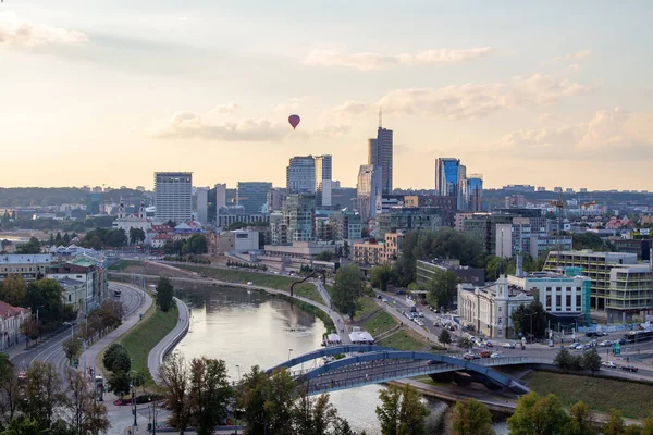 Gün batımında Vilnius Panoraması. Şehir binaları. Ufuktaki gökdelenler. Şehrin üzerinde mavi gökyüzü. Gün batımında bulutlar ve güneş. Yaz akşamı. Hafta sonu sakin bir gün.