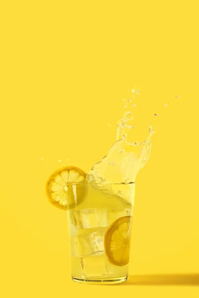 Vaso Refrescante Limonada Donde Hielo Cae Hace Chapoteo Fondo Amarillo — Foto de Stock