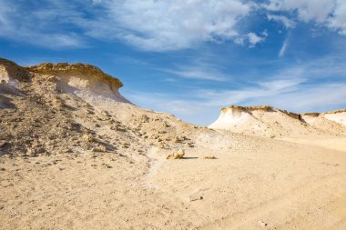 Çölde rüzgarın etkisiyle oluşmuş kayaları olan bir Zekreet çölü. Açık gökyüzünün altında bulutlu doğal manzara. Erozyondan dolayı, yerel kaya oluşumları mantarları andırıyor.