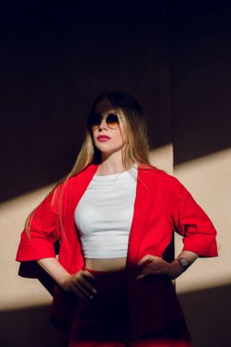 Kırmızı elbiseli genç sarışın bir kızın portresi. Güneşin acımasız gölgeleri üzerine düşüyor. Kız el ele tutuşuyor..