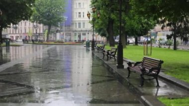 Lviv şehrinin merkezinde, Ukrayna 'nın yeşil banklarıyla taş kaldırımlara sağanak yağmur yağıyor.