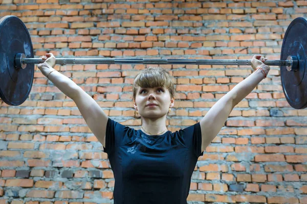 Una joven enganchada al crossfit. Sostiene la barra sobre su cabeza . — Foto de Stock