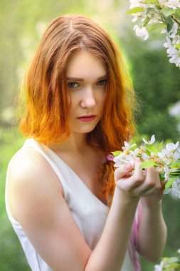 Genç bir kız bir çiçeklenme tree yakınındaki açık havada büyük portresi. Bahar ve çiçekler.