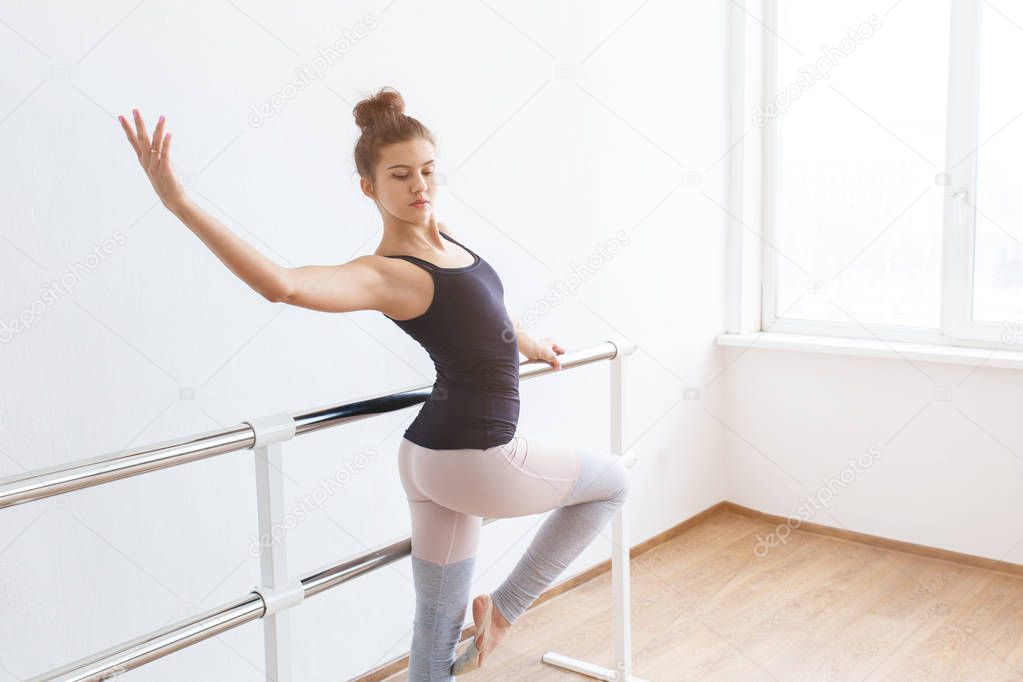 Young and graceful ballerina in the gym performing exercises.