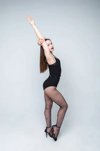 Gyönyörű lány táncos fekete ruhát jelentő világos háttér. A lány hosszú haja. — Stock Fotó