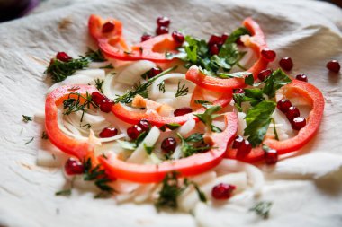 Tabakta ince bir pastanın üzerindeki sebzeler. Biber, soğan, nar, kavrulmuş et için tortilla.