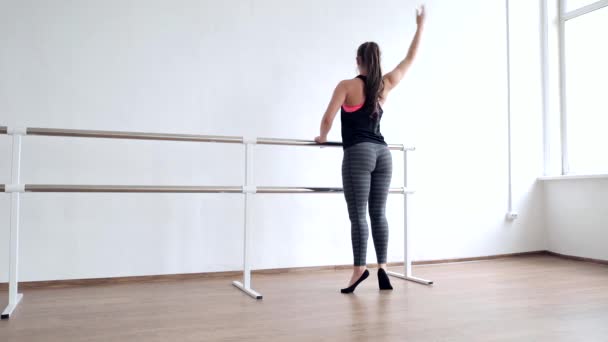 一个年轻的女孩是一个有抱负的舞蹈家 女孩芭蕾舞演员与郁郁葱葱的臀部在工作室进行芭蕾舞练习 — 图库视频影像