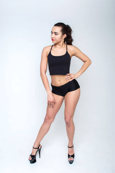 Красивая девушка на высоких каблуках в черной одежде для танцев. Голые ноги с гладкой кожей. Девушка улыбается
.