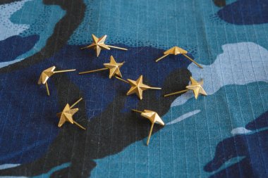 Mavi kamuflaj kumaşta omuz kayışları için altın yıldızlar. Rus askerlerinin ve hizmetlerinin askeri amblemleri. İnsan yok