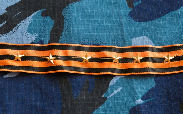 Gold stars, St. George ribbon on blue camouflage fabric. Military emblems of Russian troops and services.