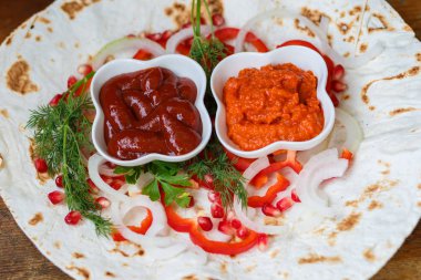 Kırmızı biber, soğan, nar ve maydanoz lavaş üzerine kavrulmuş et, sosis veya sosis ketçap ve Ermeni çerez Aivar ile servis edilir. Yukarıdan görünüm.