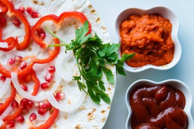 Kırmızı biber, soğan, nar ve maydanoz lavaş üzerine kavrulmuş et, sosis veya sosis ketçap ve Ermeni çerez Aivar ile servis edilir. Yukarıdan görünüm.