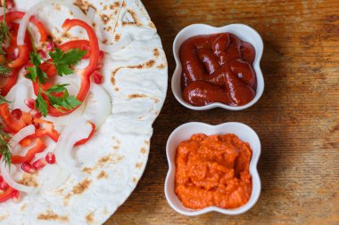 Kırmızı biber, soğan, nar ve maydanoz lavaş üzerine kavrulmuş et, sosis veya sosis ketçap ve Ermeni çerez Aivar ile servis edilir. Yukarıdan görünüm.
