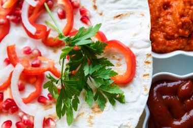 Kırmızı biber, soğan, nar ve maydanoz lavaş üzerine kavrulmuş et, sosis veya sosis ketçap ve Ermeni çerez Aivar ile servis edilir. Yukarıdan görünüm.