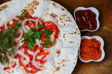 Kırmızı biber, soğan, nar ve maydanoz lavaş üzerine kavrulmuş et, sosis veya sosis ketçap ve Ermeni çerez Aivar ile servis edilir. Yukarıdan görünüm.