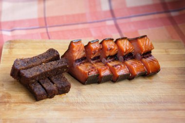 Bira atıştırması. Kızarmış siyah ekmek ve kırmızı füme balık. Siyah ekmek ve füme balık parçalara kesilmiş, ahşap bir tahta üzerinde yalan.