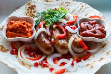 Ketçap lı pide de kızarmış domuz sosisi ve sebzeli Ermeni mezesi Aivar. Lavaş, kırmızı biber, soğan, sosis. Oktoberfest gıda, pub kavramı